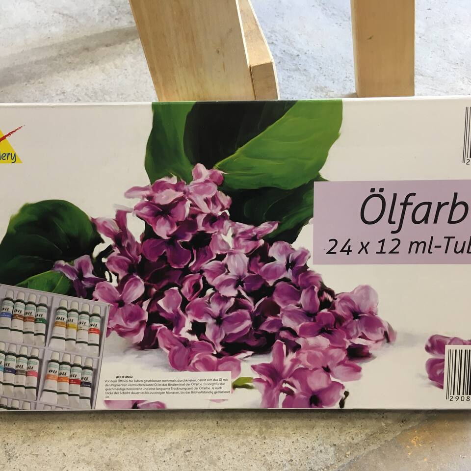Verpackung mit 24 Tuben Ölfarben der Marke Creative Gallery, darauf ein Bild von lila Fliederblüten und grünen Blättern