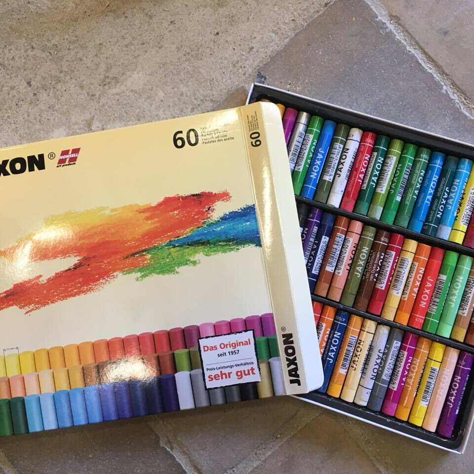 Geöffnete Packung mit 60 farbigen Wachsmalstiften der Marke Jaxon auf einem Steinboden