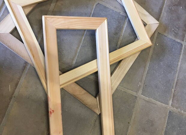 Mehrere rechteckige Holzrahmen liegen auf einem gefliesten Boden übereinander.