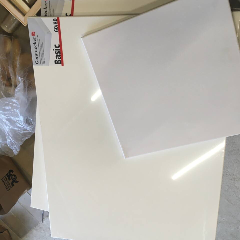 Mehrere weiße Keilrahmen unterschiedlicher Größe liegen auf einem Boden, im Hintergrund ist eine Verpackung mit der Aufschrift 'Gerflor Basic' zu sehen.